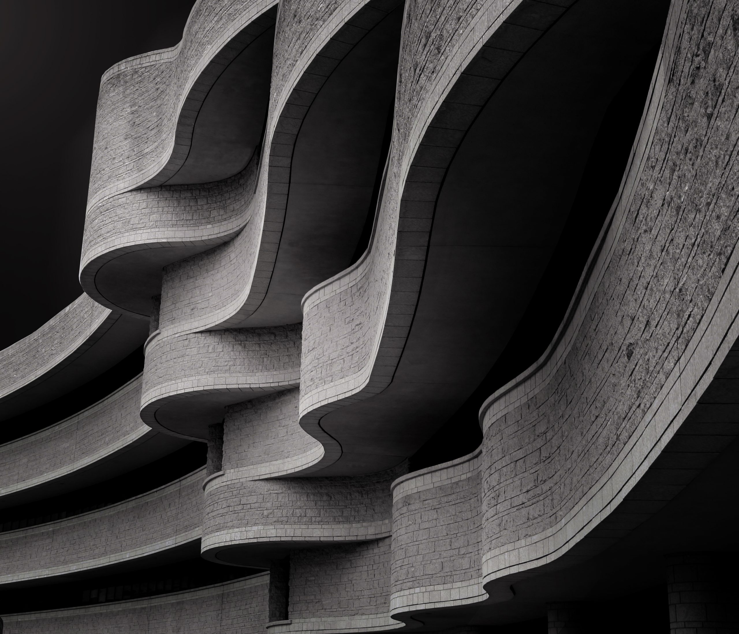 Low angle greyscale of a building with modern brutalist architecture under the sunlight