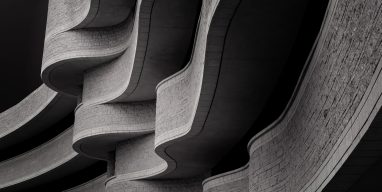 Low angle greyscale of a building with modern brutalist architecture under the sunlight